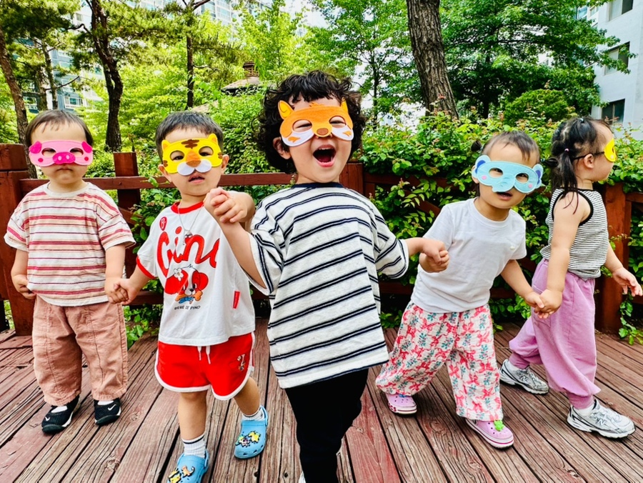 삼산그린어린이집 아이들이 가면을 쓰고 야외에서 손잡고 즐겁게 노는 모습